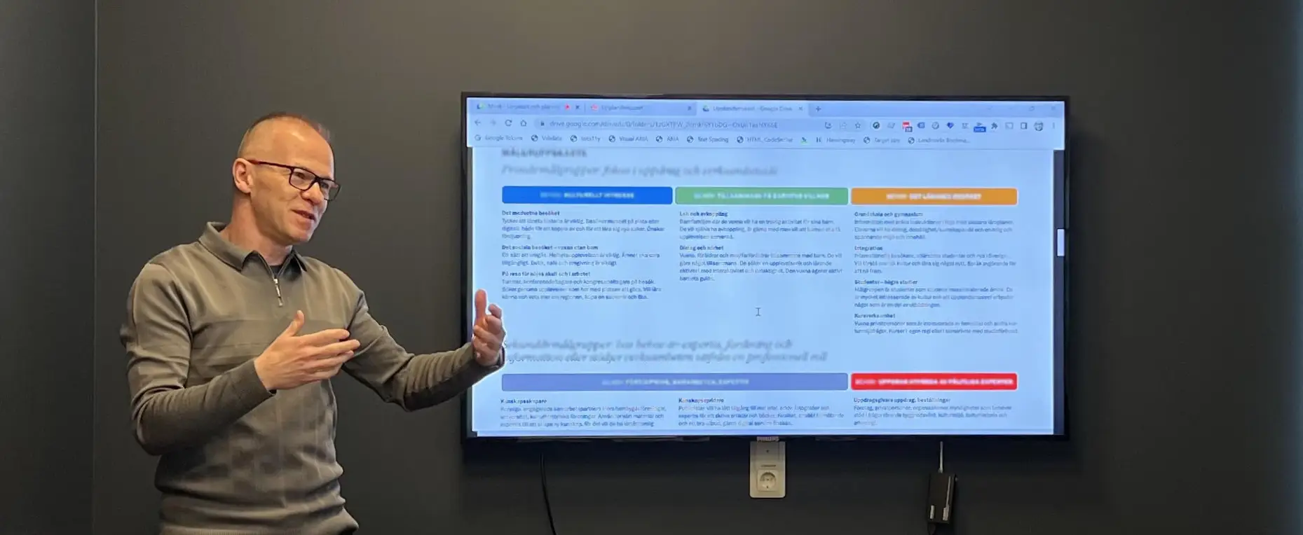 James presenting during a workshop. He is gesticulating with his hands by a large screen.